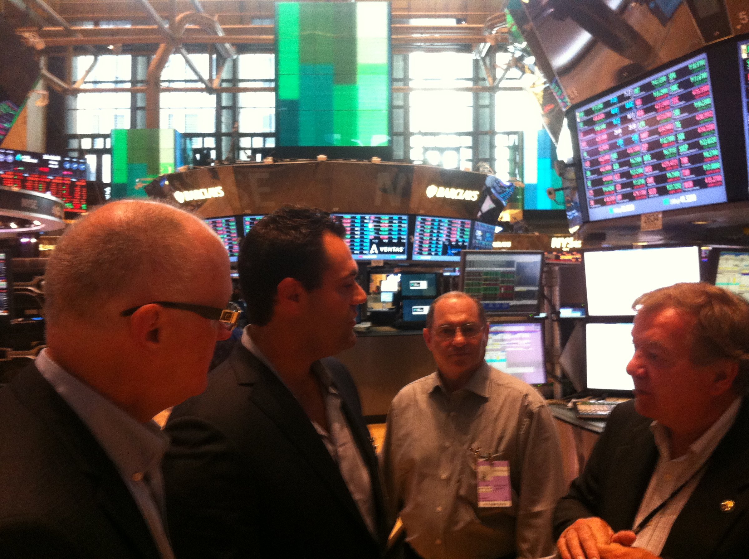 Members of the Champion Pain Care party gathered on the New York Stock Exchange trading floor beneath market displays.